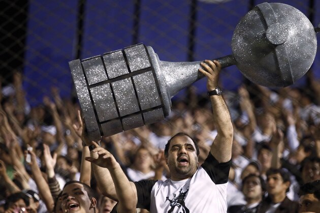Paraguay Olimpia soccer fan holds up a replica of a trophy before the first leg final of the Copa Libertadores match against Brazil's Atletico Mineiro in Asuncion, Paraguay, Wednesday, July 17, 2013. (AP Photo/Jorge Saenz)
