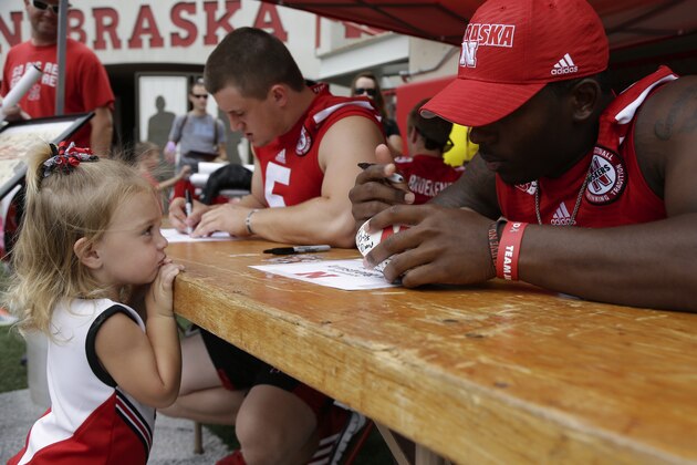 Olivia Foster, 2, of Eagle, Neb., watches as Nebraska quarterback Tommy Armstrong signs her football during the annual NCAA college football fan day in Lincoln, Neb., Friday, Aug. 1, 2014. Nebraska goes into the 2014 season looking to become relevant again nationally. The Cornhuskers finished 2013 outside the Top 25 for the first time since 2008, and they haven't ended a season in the top 10 since 2001. This year Wisconsin and Iowa are picked to finish ahead of the Huskers in the new West Division. (AP Photo/Nati Harnik)