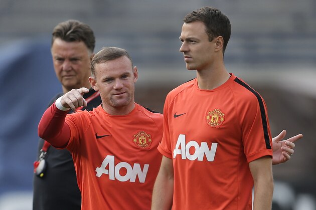 Manchester United's Wayne Rooney, left, talks with Jonny Evans as manager Louis van Gaal, left, watches during training for the their 2014 Guinness International Champions Cup soccer match against Real Madrid at Michigan Stadium in Ann Arbor, Mich., Friday, Aug. 1, 2014. (AP Photo/Paul Sancya)