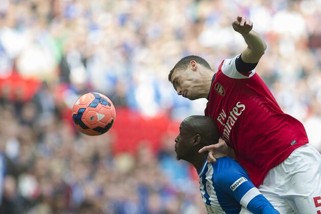 Arsenal's Thomas Vermaelen, top head the ball with Wigan Athletic's Marc-Antoine Fortune during their English FA Cup semifinal soccer match, at the Wembley Stadium in London, Saturday, April 12, 2014. (AP Photo/Bogdan Maran)