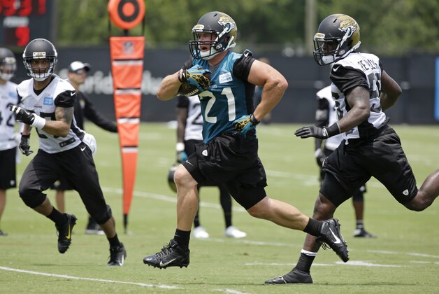 Jacksonville Jaguars running back Toby Gerhart (21) makes a move to get by Jacksonville Jaguars cornerback Dwayne Gratz, left, and linebacker LaRoy Reynolds, right, during an NFL organized team activities football practice in Jacksonville, Fla., Tuesday, May 27, 2014. (AP Photo/John Raoux)