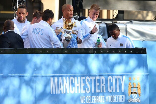 MANCHESTER, ENGLAND - MAY 12:  Vincent Kompany of Manchester City lifts the Barclays Premier League trophy aloft outside Manchester Town Hall as Joe Hart gives the thumbs up at the start of the Manchester City victory parade around the streets of Manchester on May 12, 2014 in Manchester, England.  (Photo by Alex Livesey/Getty Images)