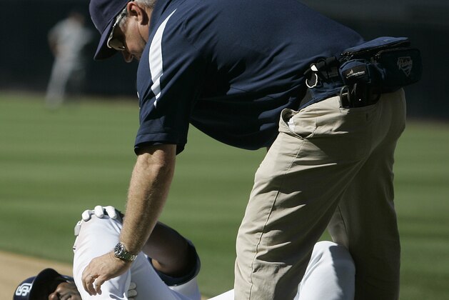 San Diego Padres' Milton Bradley is attended to by trainer Todd Hutchinson after Bradley was injured while being restrained by manager Bud Black during an altercation in the eighth inning of the Padres' 7-3 loss to the Colorado Rockies in their baseball game in San Diego, Sunday Sept. 23, 2007.  (AP Photo/Lenny Ignelzi)