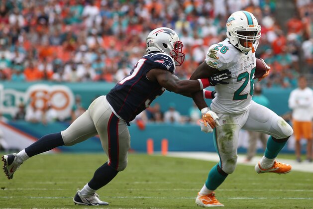 Miami Dolphins running back Lamar Miller (26) gets away from a tackle by New England Patriots cornerback Alfonzo Dennard (37) during the second half of an NFL football game, Sunday, Dec. 15, 2013, in Miami Gardens, Fla. (AP Photo/J Pat Carter)