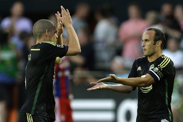 Los Angeles Galaxy forward Landon Donovan, right, is greeted by Seattle Sounders midfielder Osvaldo Alonso, left, after Donovan scored a coal against Bayern Munich in the second half of the MLS soccer All-Star match, Wednesday, Aug. 6, 2014, in Portland, Ore. (AP Photo/Ted S. Warren)