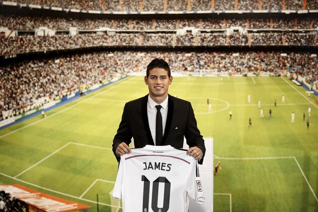 New Real Madrid player James Rodriguez, from Colombia, holds his new shirt and poses for photographers during his official presentation at the Santiago Bernabeu stadium in Madrid, Spain, Tuesday, July 22, 2014, after signing for Real Madrid. Real Madrid have signed Rodriguez from Monaco on a six-year contract. (AP Photo/Daniel Ochoa de Olza)