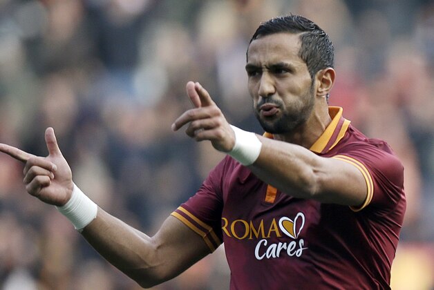 AS Roma's Mehdi Benatia, of Morocco, left, mimics shooting as he celebrates after scoring during a Serie A soccer match against Catania in Rome's Olympic Stadium, Sunday, Dec. 22, 2013. (AP Photo/Gregorio Borgia)
