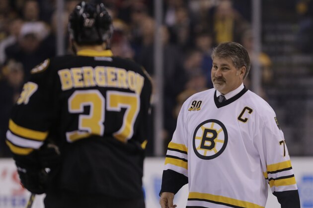 Boston Bruins great Ray Bourque smiles as he passes Patrice Bergeron prior to the first period of an NHL hockey game, Monday, March 24, 2014, in Boston. (AP Photo/Charles Krupa)