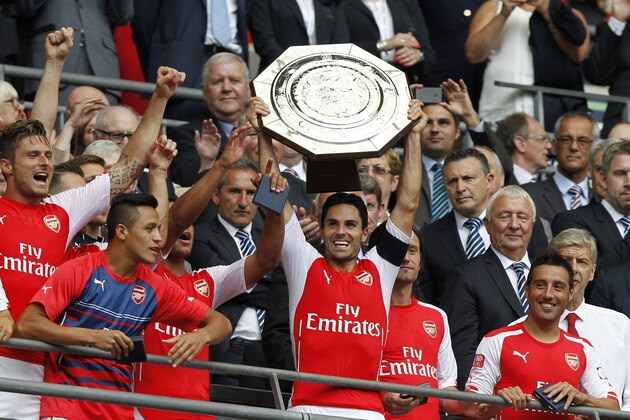 Arsenal's Mikel Arteta raises the trophy after their win against Manchester City at the end of their English Community Shield soccer match at Wembley Stadium in London, Sunday, Aug. 10, 2014. (AP Photo/Sang Tan)