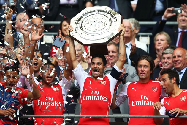 LONDON, ENGLAND - AUGUST 10: Captain Mikel Arteta of Arsenal holds up the trophy alongside team-mates Alex Oxlade-Chamberlain (L) Tomas Rosicky and Santi Cazorla after winning the FA Community Shield match between Manchester City and Arsenal at Wembley Stadium on August 10, 2014 in London, England.  (Photo by Clive Mason/Getty Images)