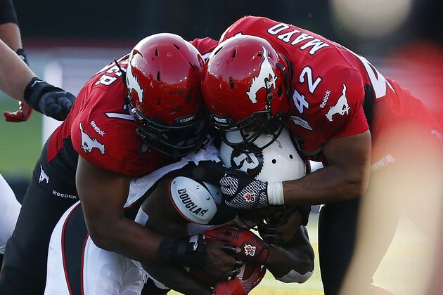 CALGARY, CANADA - AUGUST 9: Junior Turner #7 and teammate Deron Mayo of the Calgary Stampeders tackles Chevon Walker #29 of the Ottawa REDBLACKS in the second half of their CFL football game August 9, 2014 at McMahon Stadium in Calgary, Alberta, Canada. (Photo by Todd Korol/Getty Images)