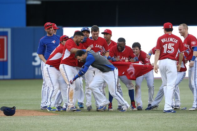 TORONTO, CANADA - AUGUST 10: Jose Bautista #19 of the Toronto Blue Jays is congratulated on his game-winning hit by teammates in the ninteenth inning during MLB game action against the Detroit Tigers on August 10, 2014 at Rogers Centre in Toronto, Ontario, Canada. (Photo by Tom Szczerbowski/Getty Images)
