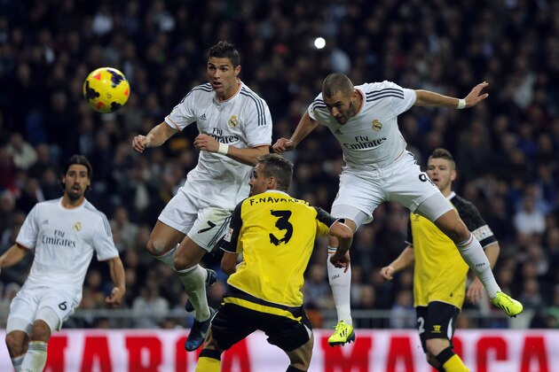Real Madrid's Karim Benzema from France, right, scores his goal in between players during a Spanish La Liga soccer match between Real Madrid and Sevilla at the Santiago Bernabeu stadium in Madrid, Spain, Wednesday Oct. 30, 2013. (AP Photo/Andres Kudacki)