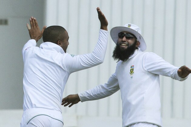 South African players  Dane Piedt, left, and Hashim Amla celebrate the wicket of Zimbabwean batsman Brendan Taylor during the cricket Test match against South Africa at the Harare Sports club, in Harare Zimbabwe Tuesday, Aug. 12, 2014. (AP Photo/Tsvangirayi Mukwazhi)