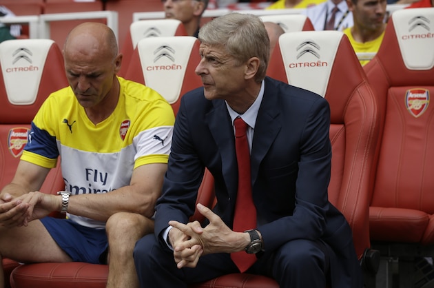 Arsenal's French manager Arsene Wenger, right, sits with his assistant Steve Bould before the start of the Emirates Cup soccer match between between Arsenal and Benfica at Arsenal's Emirates Stadium in London, Saturday, Aug. 2, 2014.  (AP Photo/Matt Dunham)