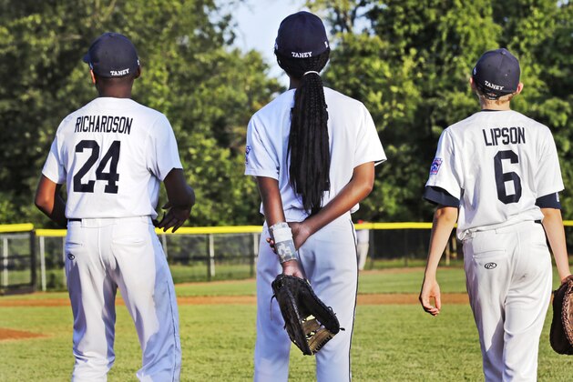 In this Aug. 6, 2014 photo, Pennsylvania's Mo'Ne Davis, center, stands with teammates Joe Richardson (24) and Erik Lipson (6) prior to facing the District of Columbia in a baseball game in the Little League Eastern Regionals at Breen Stadium in Bristol, Conn. Davis and New Jersey's Kayla Roncin are competing to make it to the Little League World Series, a rare feat for girls.  (AP Photo/Charles Krupa)
