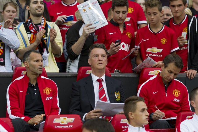 Manchester United's new manager Louis van Gaal, centre, takes his seat along side assistant manager Ryan Giggs, left, prior to his team's pre-season friendly soccer match,  against Valencia at Old Trafford Stadium, Manchester, England, Tuesday Aug. 12, 2014. (AP Photo/Jon Super)