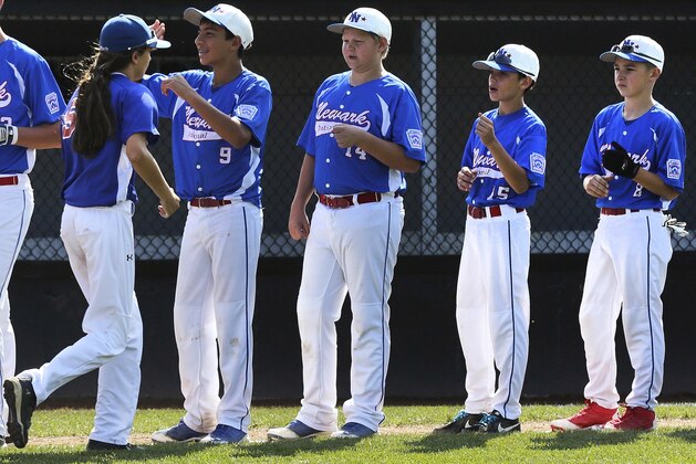 In this Aug. 6, 2014, photo, New Jersey's Kayla Roncin, of Toms River, N.J., is greeted by Delaware players during team introductions prior to their baseball game in the Little League Eastern Regionals at Breen Stadium in Bristol, Conn.Roncin and Pennsylvania's Mo’Ne Davis are competing to make it to the Little League World Series, a rare feat for girls.  (AP Photo/Charles Krupa)