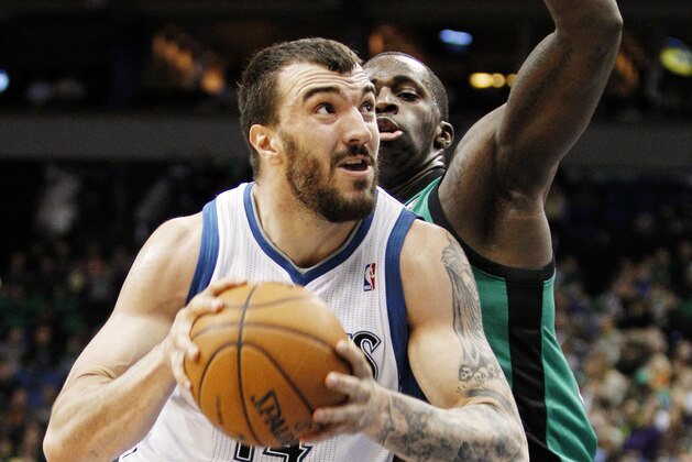 Minnesota Timberwolves center Nikola Pekovic (14) drives around Boston Celtics forward Brandon Bass for a basket during the first half of an NBA basketball game Monday, April 1, 2013, in Minneapolis. (AP Photo/Genevieve Ross)