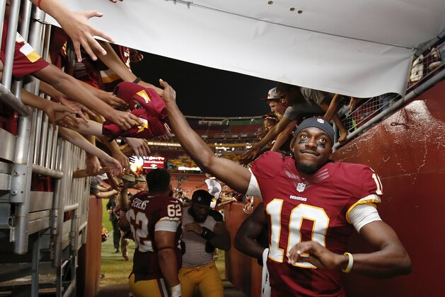 Washington Redskins quarterback Robert Griffin III reaches for fans' hands as he leaves the field after an NFL football preseason game against the New England Patriots in Landover, Md., Thursday, Aug. 7, 2014. The Redskins defeated the Patriots 23-6. (AP Photo/Alex Brandon)