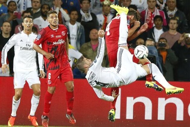Real Madrid’s Sergio Ramos jumps for the ball with Sevilla’s Grzegorz Krychowiak during the UEFA Super Cup soccer match between Real Madrid and Sevilla in Cardiff City Stadium, in Cardiff, Wales, Tuesday, Aug. 12, 2014. (AP Photo/Alastair Grant)