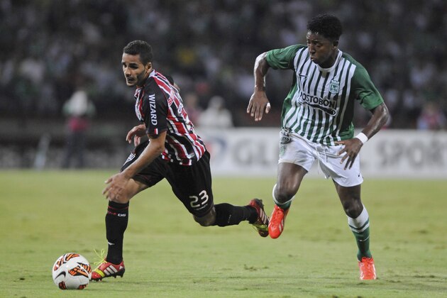 Douglas of Brazil's Sao Paulo, left, dribbles past Oscar Murillo of Colombia's Atletico Nacional at a Copa Sudamericana quarter final soccer match in Medellin, Colombia, Wednesday, Nov. 6, 2013. (AP Photo/Luis Benavides)