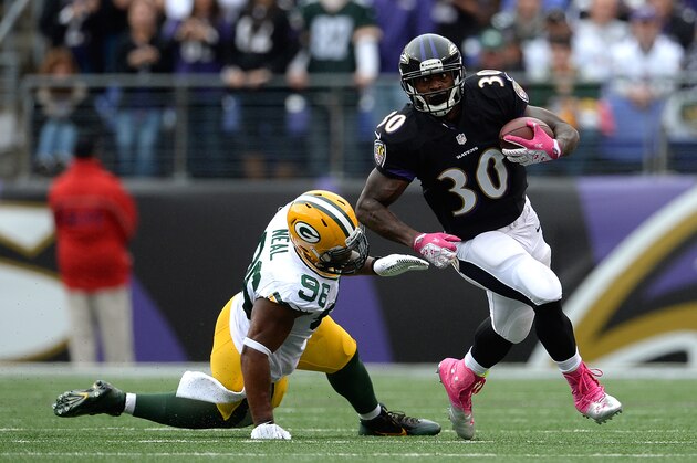 BALTIMORE, MD - OCTOBER 13:  Bernard Pierce #30 of the Baltimore Ravens avoids the tackle of Mike Neal #96 of the Green Bay Packers in the first half during a game at M&T Bank Stadium on October 13, 2013 in Baltimore, Maryland.  (Photo by Patrick McDermott/Getty Images)