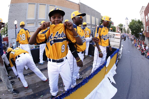 Members of the Jackie Robinson West Little League team from Chicago, Ill., ride in the Little League Grand Slam Parade as it makes its way through downtown Williamsport, Pa., Wednesday, Aug. 13, 2014. The Little League World Series tournament begins Thursday, August 14, in South Williamsport, Pa..  (AP Photo/Gene J. Puskar)