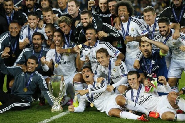 Real Madrid players pose with the trophy after winning the UEFA Super Cup soccer match between Real Madrid and Sevilla in Cardiff City Stadium, in Cardiff, Wales, Tuesday, Aug. 12, 2014. (AP Photo/Alastair Grant)