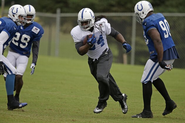 Indianapolis Colts running back Trent Richardson (34) runs past defensive end Cory Redding (90) during NFL football training camp Tuesday, Aug. 12, 2014, in Anderson, Ind. (AP Photo/Darron Cummings)