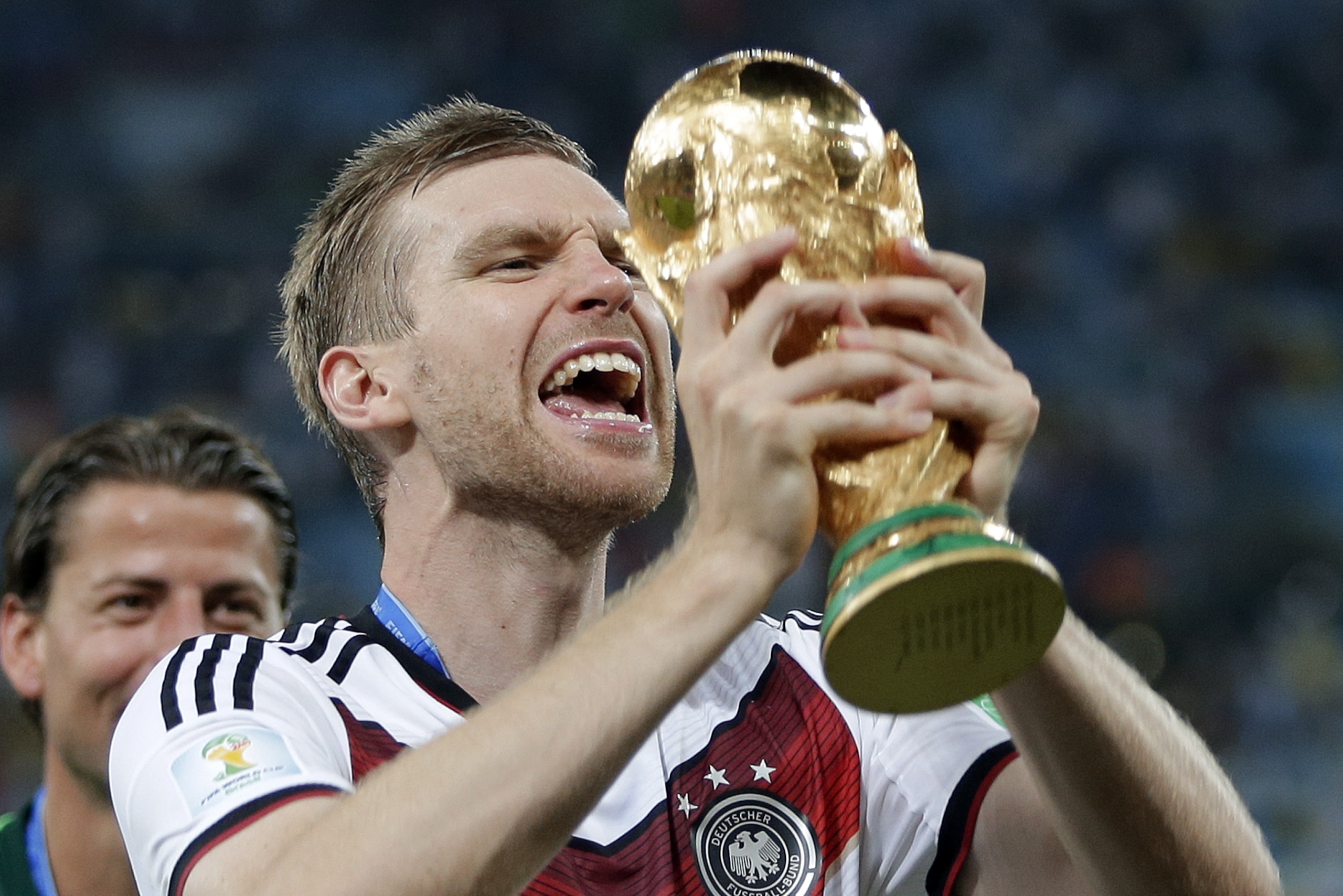 Germany's Per Mertesacker celebrates with the trophy after the World Cup final soccer match between Germany and Argentina at the Maracana Stadium in Rio de Janeiro, Brazil, Sunday, July 13, 2014. Germany won the match 1-0. (AP Photo/Matthias Schrader)