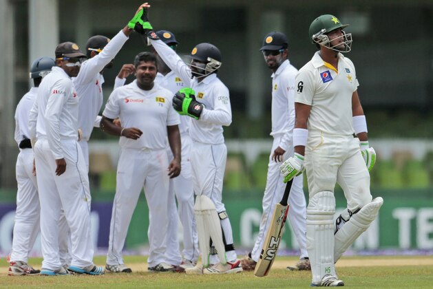 Pakistan's Khurram Manzoor leaves the pitch after being dismissed as Sri Lankan cricketers celebrate during the second day of the second test cricket match between Sri Lanka and Pakistan in Colombo, Sri Lanka, Friday, Aug. 15, 2014. (AP Photo/Eranga Jayawardena)