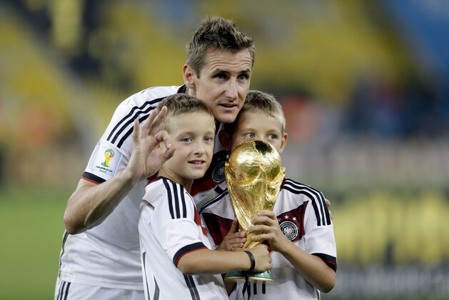 Germany's Miroslav Klose poses with the World Cup trophy and his sons following their 1-0 victory over Argentina after the World Cup final soccer match between Germany and Argentina at the Maracana Stadium in Rio de Janeiro, Brazil, Sunday, July 13, 2014. (AP Photo/Natacha Pisarenko)