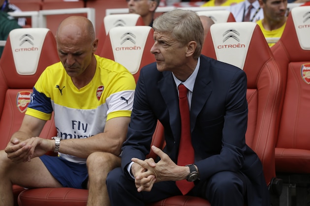 Arsenal's French manager Arsene Wenger, right, sits with his assistant Steve Bould before the start of the Emirates Cup soccer match between between Arsenal and Benfica at Arsenal's Emirates Stadium in London, Saturday, Aug. 2, 2014.  (AP Photo/Matt Dunham)