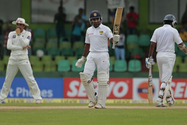 Sri Lankan batsman Mahela Jayawardene, center, celebrates scoring a fifty in his final test innings during the fourth day of the second test cricket match against Pakistan in Colombo, Sri Lanka, Sunday, Aug.17, 2014. (AP Photo/Eranga Jayawardena)