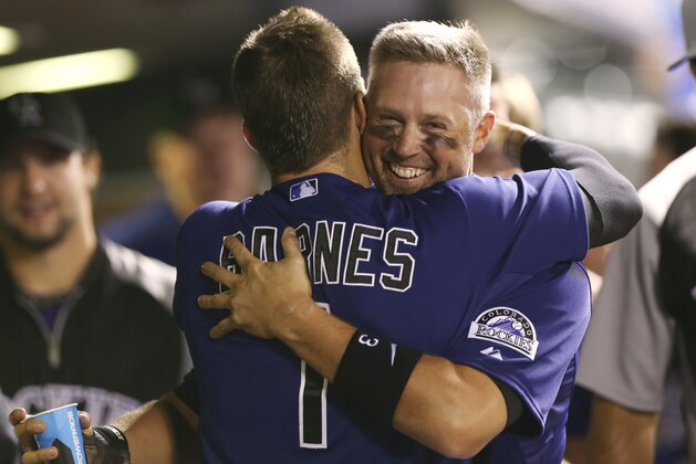 Colorado Rockies' Brandon Barnes, front, hugs teammate Michael Cuddyer after he scored on a single hit by pinch-hitter Drew Stubbs against the Cincinnati Reds in the eighth inning of the Rockies' 10-5 victory in a baseball game in Denver on Sunday, Aug. 17, 2014. The game is being made up after it was postponed on Saturday by a water main break that left the stadium waterless. (AP Photo/David Zalubowski)