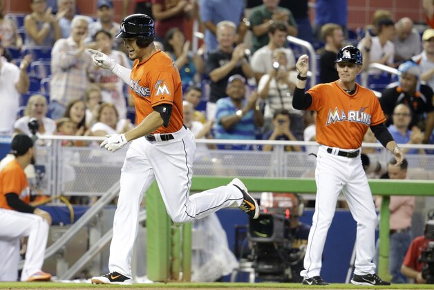 Miami Marlins' Giancarlo Stanton, left, rounds third base after hitting a three-run home run in the first inning during a baseball game against the Arizona Diamondbacks, Sunday, Aug.17, 2014, in Miami. At right is Miami Marlins third base coach Brett Butler. (AP Photo/Lynne Sladky)