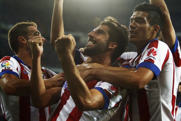 Atletico's Raul Garcia, center, celebrates his goal with his teammates during a Spanish Supercup first leg soccer match between Real Madrid and Atletico Madrid at Santiago Bernabeu stadium in Madrid, Spain, Tuesday, Aug. 19, 2014. (AP Photo/Andres Kudacki)