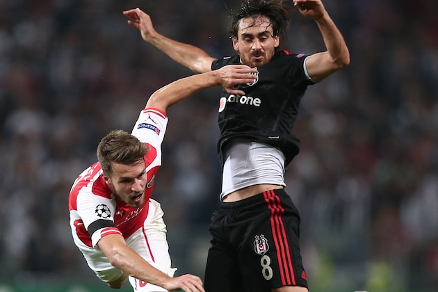 Besiktas's Veli Kavlak, rear, and Aaron Ramsey of Arsenal fight for the ball during their Champions League play-off first leg soccer match in Istanbul, Turkey, Tuesday, Aug. 19, 2014. (AP Photo)
