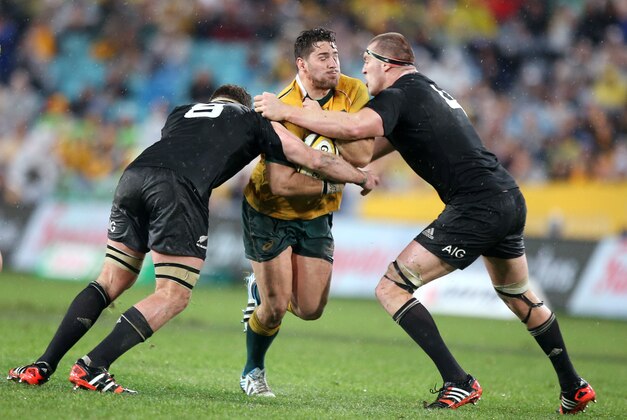 Australia's Nathan Charles, center, charges through the defense of New Zealand's Kieran Read, left, and Brodie Retallic during their Bledisloe Cup rugby union test match in Sydney, Saturday, Aug. 16, 2014. The game is a 12-all draw. (AP Photo/Rick Rycroft)