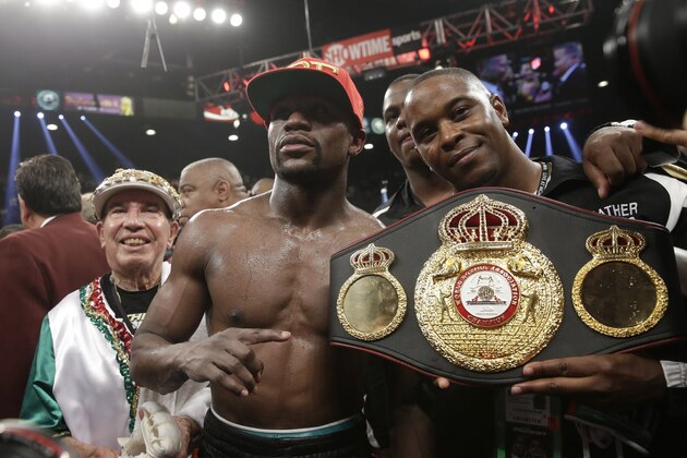 Floyd Mayweather Jr., center, poses with his corner and a champion's belt after his WBC-WBA welterweight title boxing fight against Marcos Maidana Saturday, May 3, 2014, in Las Vegas. Mayweather won the bout by majority decision. (AP Photo/Isaac Brekken)
