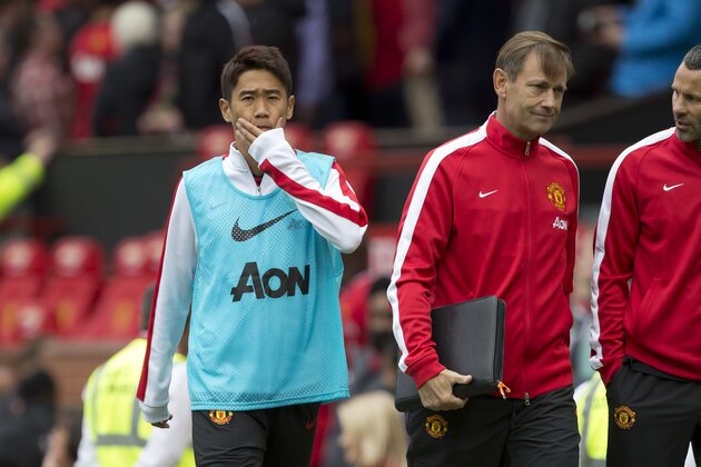 Manchester United's Shinji Kagawa, left, wipes his face as he walks from the pitch after his team's 2-1 loss to Swansea City in their English Premier League soccer match at Old Trafford Stadium, Manchester, England, Saturday Aug. 16, 2014. (AP Photo/Jon Super)