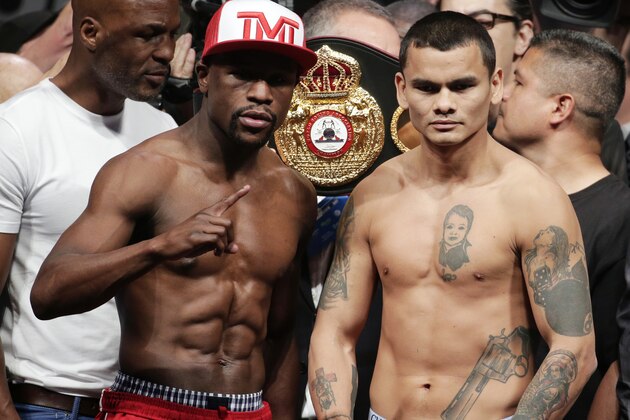 Floyd Mayweather Jr., left, poses on the scales with Marcos Maidana during the official weigh-in at the MGM Grand Hotel in Las Vegas, Friday, May 2, 2014. Mayweather is to face Maidana in a welterweight title fight on Saturday. (AP Photo/Chris Carlson)