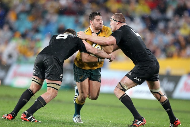 Australia's Nathan Charles, center, charges through the defense of New Zealand's Kieran Read, left, and Brodie Retallic during their Bledisloe Cup rugby union test match in Sydney, Saturday, Aug. 16, 2014. The game is a 12-all draw. (AP Photo/Rick Rycroft)