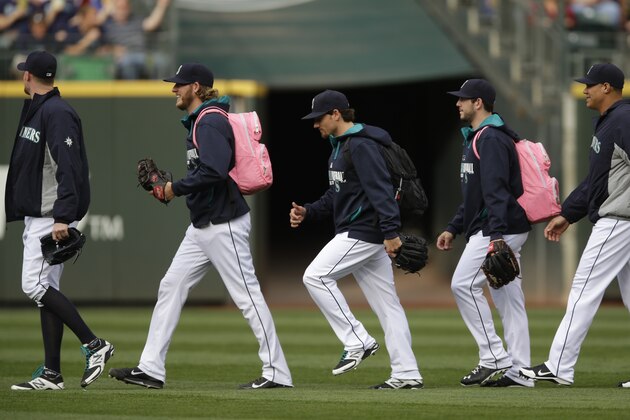 Seattle Mariners pitchers, including rookies wearing pink backpacks, walk to the bullpen before a baseball game between the Seattle Mariners and the Boston Red Sox, Wednesday, June 25, 2014, in Seattle. (AP Photo/Ted S. Warren)