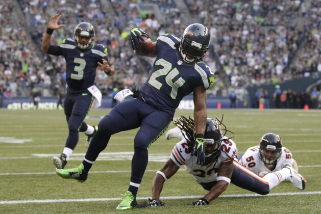 Seattle Seahawks' Marshawn Lynch (24) scores as quarterback Russell Wilson (3) reacts behind and Chicago Bears' Danny McCray hits the turf in the first half of an preseason NFL football game, Friday, Aug. 22, 2014, in Seattle. (AP Photo/Stephen Brashear)
