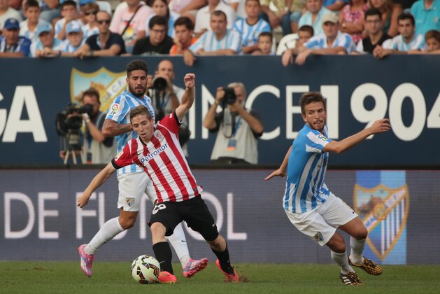 MALAGA, SPAIN - AUGUST 23: Muniain (C) of Athletic Club Bilbao controls the ball against Samuel (L) and Ignacio Camacho (R) of Malaga CF during the La Liga match between Malaga CF and Athletic Club Bilbao at La Rosaleda Stadium on August 23, 2014 in Malaga, Spain. (Photo by Sergio Camacho/Getty Images)