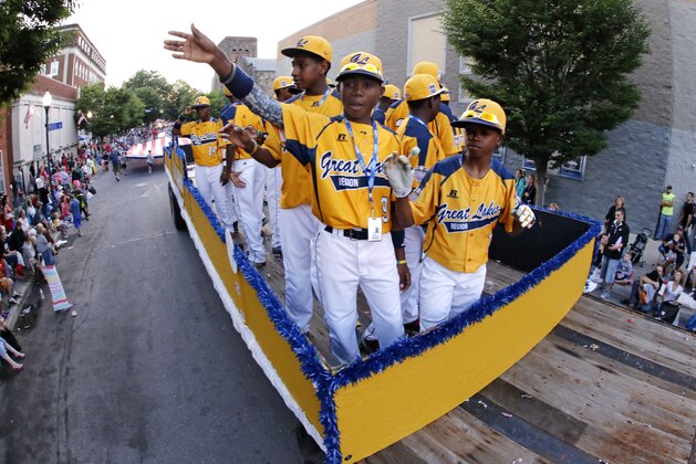 Members of the Jackie Robinson West Little League team from Chicago, Ill., ride in the Little League Grand Slam Parade as it makes its way through downtown Williamsport, Pa., Wednesday, Aug. 13, 2014. The Little League World Series tournament begins Thursday, August 14, in South Williamsport, Pa..  (AP Photo/Gene J. Puskar)