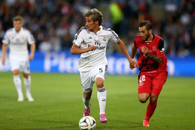 CARDIFF, WALES - AUGUST 12:  Fabio Coentrao of Real Madrid is pursued by Aleix Vidal of Sevilla during the UEFA Super Cup between Real Madrid and Sevilla FC at Cardiff City Stadium on August 12, 2014 in Cardiff, Wales.  (Photo by Clive Mason/Getty Images)