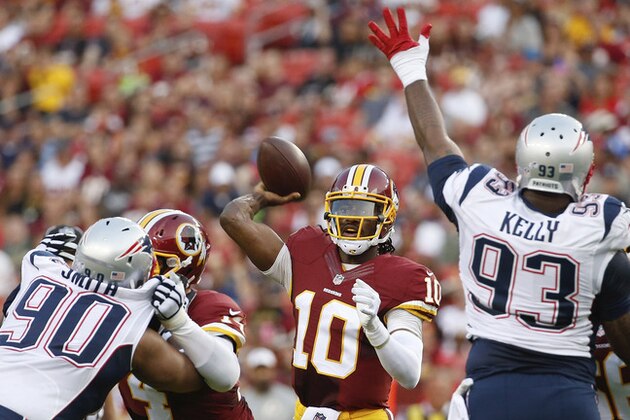 Washington Redskins quarterback Robert Griffin III passes between New England Patriots defensive end Will Smith (90) and defensive tackle Tommy Kelly (93) during the first half of an NFL football preseason game in Landover, Md., Thursday, Aug. 7, 2014. (AP Photo/Alex Brandon)